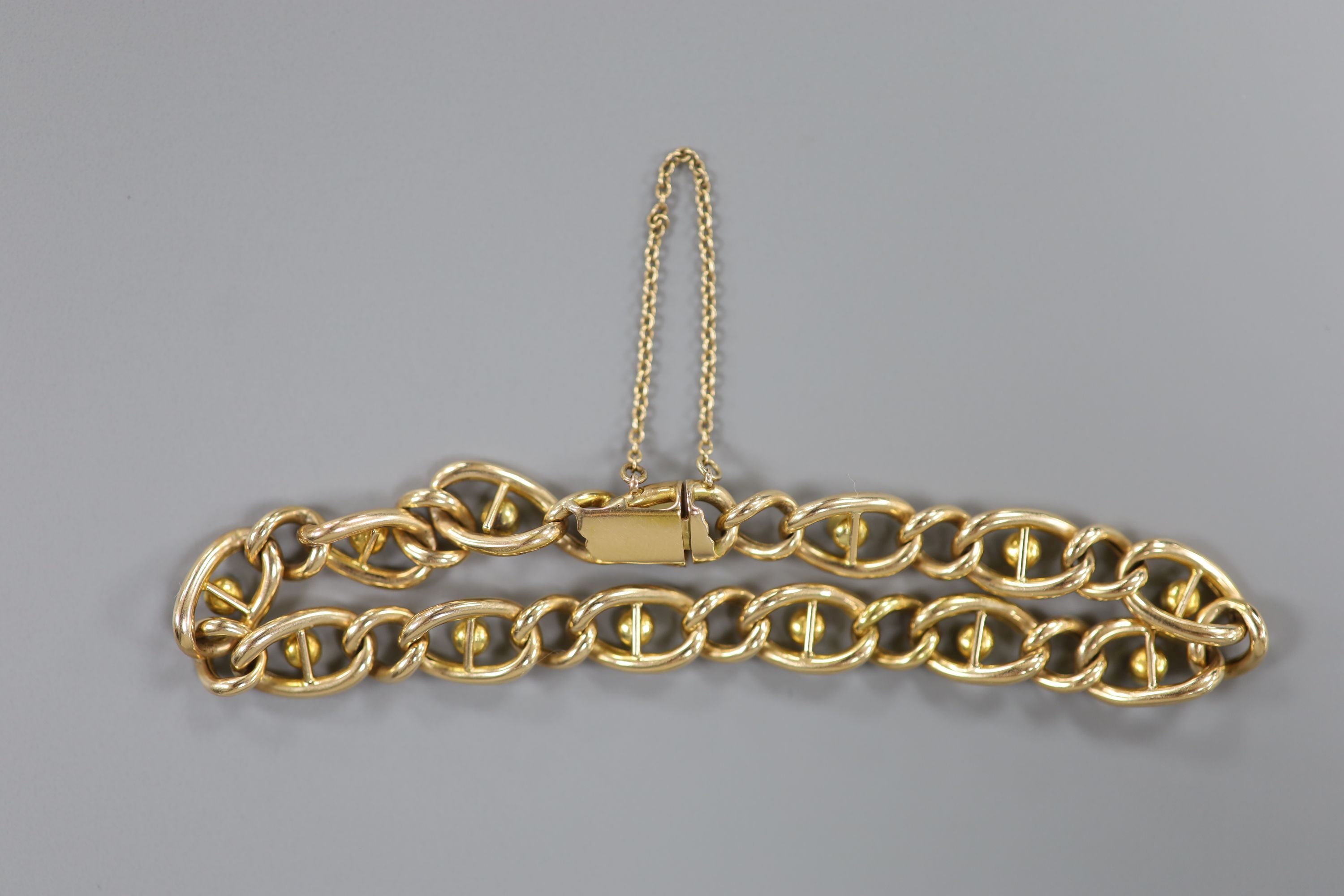 An early 20th century yellow metal and twelve stone white opal set oval link bracelet, 19cm, gross 11.9 grams.